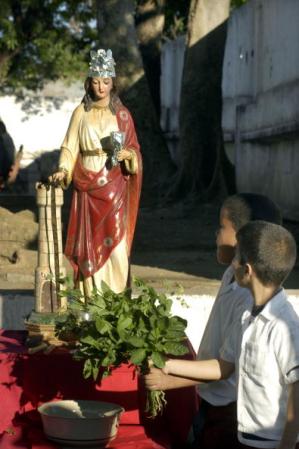 Niños ofrendan dinero a Santa Bárbara.