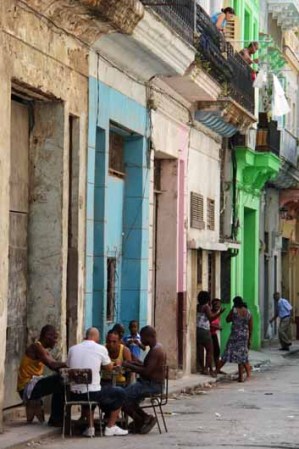 19 DE ENERO: Un retrato de la vida diaria de los cubanos en La Habana, donde los hombres juegan dominó en una mesa en la calle, mientras las mujeres conversan.