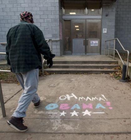 Un residente de South Philadelphia, Pennsylvania, ingresa a votar en una escuela en la que se lee un cartel a favor del presidente Obama.