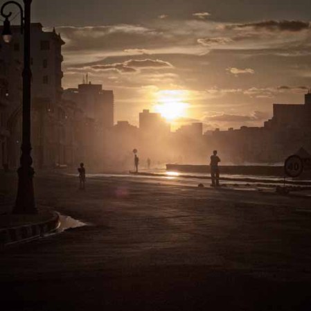 28 DE ENERO: Siluetas de caminantes, niños y fotógrafos a lo largo del Malecón al atardecer.