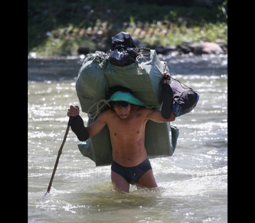 Un trabajador se despoja de casi toda su ropa para atravesar el rio Suchiate.