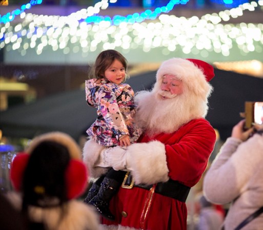 LONDRES, INGLATERRA - Una nenita posa en brazos de Santa en un bazar navideño alemán.