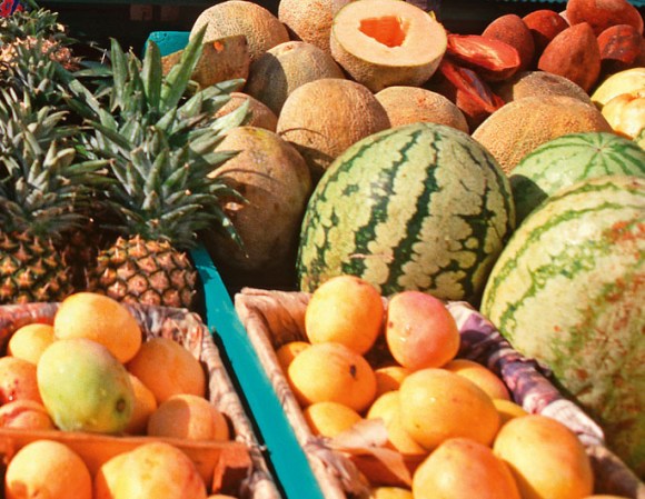 Mesa repleta de frutas caribeñas, entre ellas Mangos, piñas y sandías.