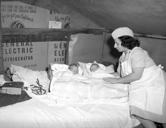 Enfermera de salud pública con unos gemelos en la choza de un trabajador inmigrante.<br />En 1931, la Junta inició un programa de licencias de partera para reducir la mortalidad infantil y promover la salud materna. 1944.