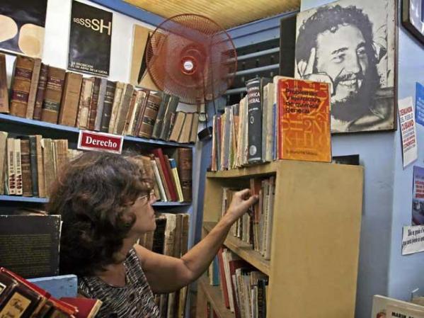 La empleada de una biblioteca pública ordena libros vetustos y maltrechos en La Habana.