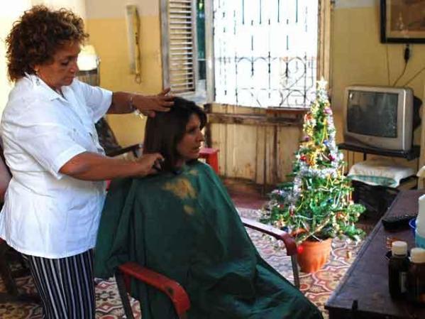 14 DE DICIEMBRE, 2007: Una peluquera que trabaja en su casa atiende a una clienta. La tradición de la Navidad regresa a la isla.
