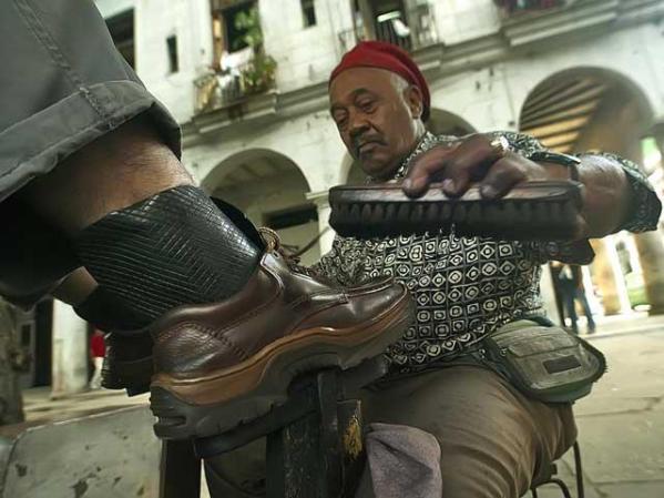 El limpiabotas Amaury Perez, 68, lustra el calzado de unos 20 hombres al día a razón de cinco pesos cada uno (20 centavos de dólar).