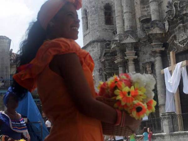 Cubanas con trajes típicos se ganan los pesos retratándose con turistas frente a la Catedral.