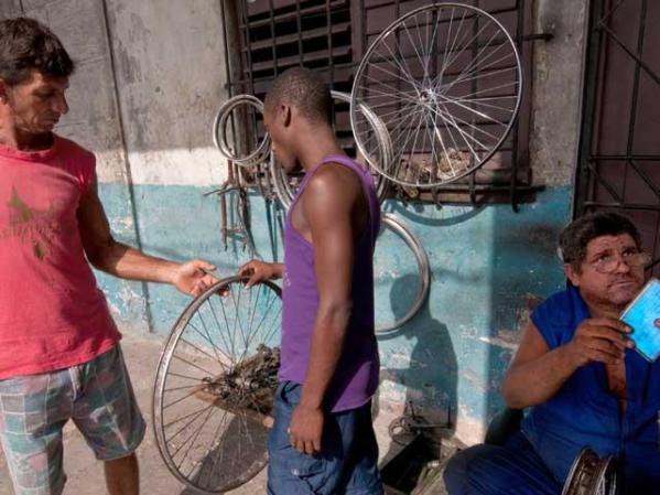 21 DE JUNIO, 2011: Un cliente inspecciona la labor de un arregla pinchazos que ahora tiene licencia para trabajar.