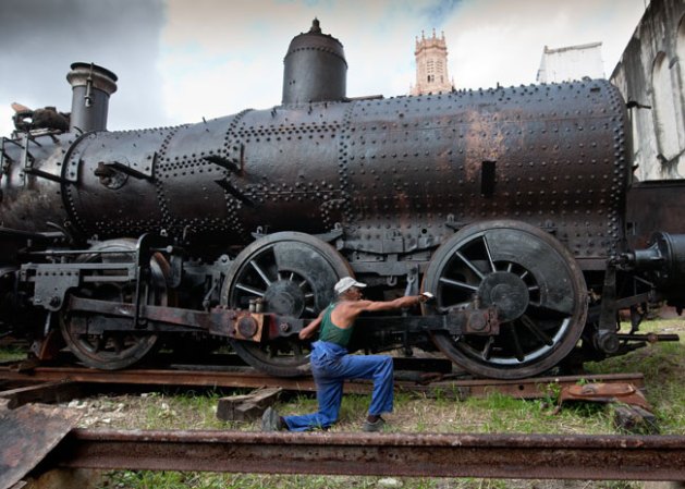 24 DE OCTUBRE, 2011: Un empleado por cuenta propia repara una locomotora del siglo XIX empleada en la zafra de azúcar.