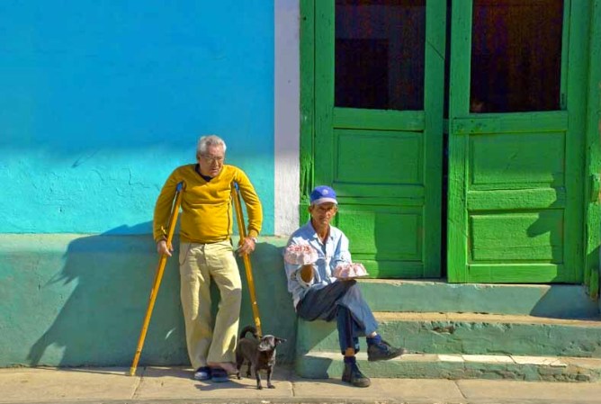16 DE ENERO: El día a día de los cubanos se convierte en una lucha diaria contra el tiempo. Dos hombres ofertan alimentos frente al portal de su casa.