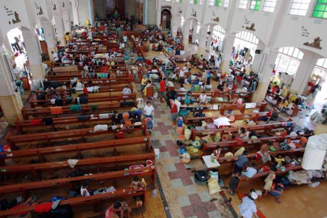 TACLOBAN, PHILIPPINES - NOVEMBER 13: Residents take shelter in a church amid scenes of devastation in the aftermath of Typhoon Haiyan on November 13, 2013 in Tacloban, Leyte, Philippines. Typhoon Haiyan, packing maximum sustained winds of 195 mph (315 kph), slammed into the southern Philippines and left a trail of destruction in multiple provinces, forcing hundreds of thousands to evacuate and making travel by air and land to hard-hit provinces difficult. Around 10,000 people are feared dead in the strongest typhoon to hit the Philippines this year. (Photo by Jeoffrey Maitem/Getty Images)