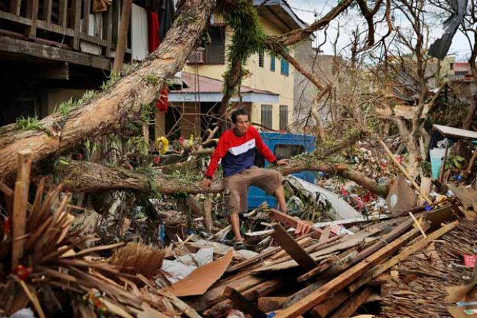 TACLOBAN, PHILIPPINES - NOVEMBER 13: A man sits amongst the wreckage of his devastated home in the aftermath of Typhoon Haiyan on November 13, 2013 in Tacloban, Leyte, Philippines. Typhoon Haiyan, packing maximum sustained winds of 195 mph (315 kph), slammed into the southern Philippines and left a trail of destruction in multiple provinces, forcing hundreds of thousands to evacuate and making travel by air and land to hard-hit provinces difficult. Around 10,000 people are feared dead in the strongest typhoon to hit the Philippines this year. (Photo by Kevin Frayer/Getty Images)