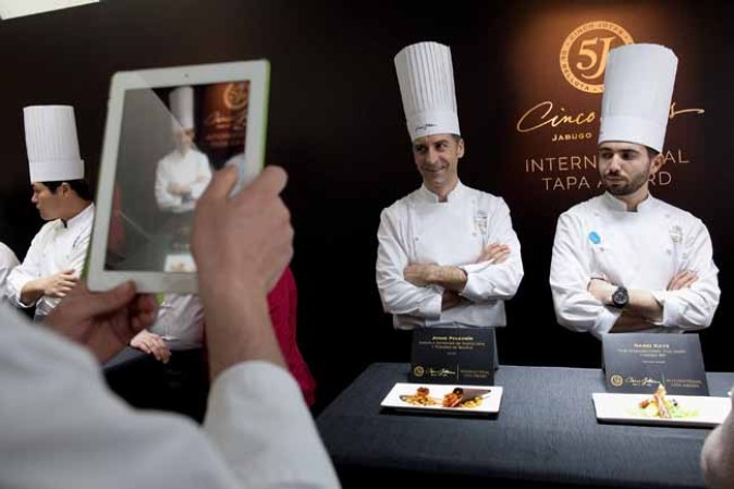 MADRID, SPAIN - MARCH 19: A person takes a picture of chef Jorge Pelegrin (2R) from the Escuela Superior de Hosteleria y Turismo de Madrid in Spain as he poses by his tapa during the Cinco Jotas International Tapa Award on March 19, 2014 in Madrid, Spain. Twelve finalist from six different countries and from some of the best culinary schools from around the world compete to make the best tapa with Iberian Bellota Ham. (Photo by Pablo Blazquez Dominguez/Getty Images)