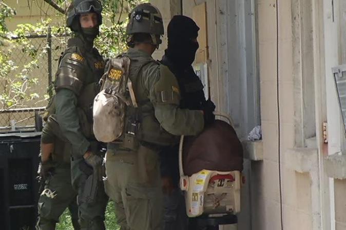Las autoridades informaron que hallaron grandes cantidades de marihuana y dinero en efectivo. Aquí un agente SWAT con un porta bebé.