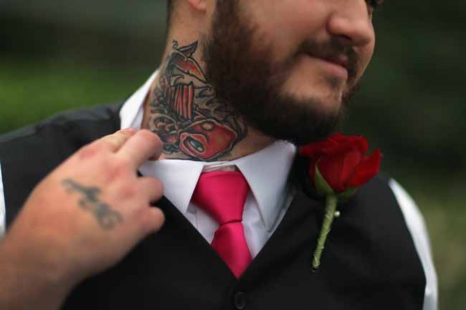 WEST PALM BEACH, FL - FEBRUARY 14: Robert Homa shows off the tattoo he said he put on his neck to cover another tattoo which was his old girlfriend�s name as he participates during a group Valentine's day wedding at the National Croquet Center on February 14, 2013 in West Palm Beach, Florida. The group wedding ceremony is put on by the Palm Beach Country Clerk & Comptroller's office and approximately 40 couple tied the knot. (Photo by Joe Raedle/Getty Images)