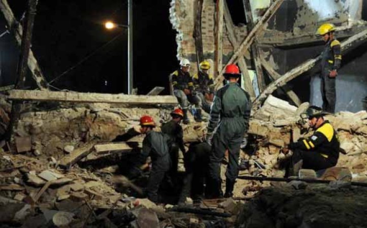 Bomberos buscan cuerpo en derrumbe.
