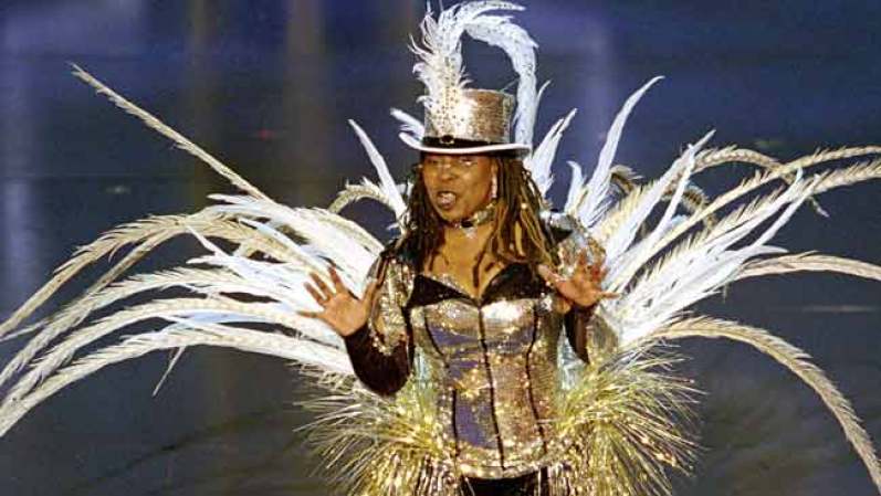 La actriz Whoopi Goldberg da la bienvenida al público con un estrafalario vestido, a la 74ª entrega del Oscar, en el Kodak Theatre de West Hollywood, el 24 de marzo del 2002. Fue la cuarta y última vez que hizo de anfitriona de la ceremonia.