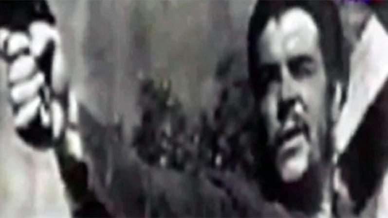 Guevara empuñando un arma y apuntado un objetivo.