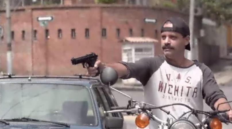 Y le apunta con una pistola en plena luz del día.