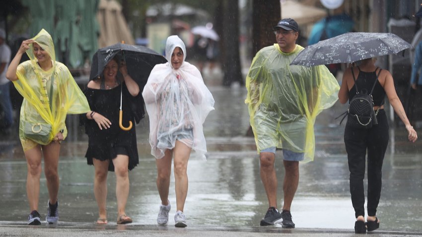 Pedestrians walk through the rain in Miami Beach, Florida.