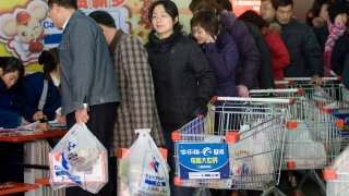 Los clientes de un supermercado con bolsas de plástico.