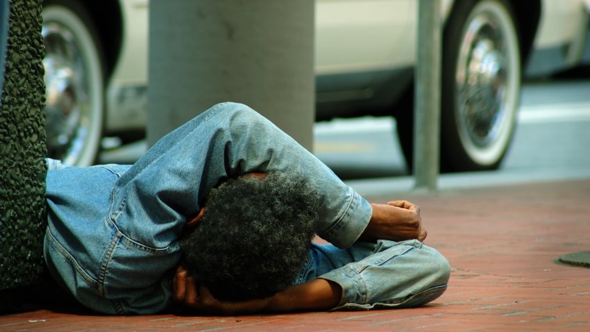 a destroyed man over the sidewalk of a big city. Car passing behind.