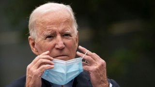 Democratic presidential nominee Joe Biden puts on a face mask while speaking to reporters at a voter mobilization center on October 26, 2020 in Chester, Pennsylvania.