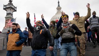 Los miembros de Proud Boys hacen un gesto con la mano mientras caminan cerca del Capitolio de los Estados Unidos en Washington, DC el miércoles 6 de enero de 2021.