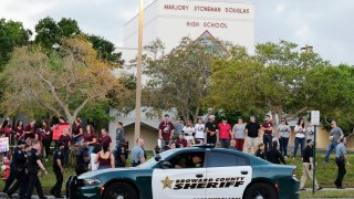 a police car drives by Marjory Stoneman Douglas High School in Parkland