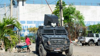 Un hombre pasa cerca a la Penitenciaria Nacional luego del ataque por parte de bandas armadas, este domingo en Puerto Príncipe