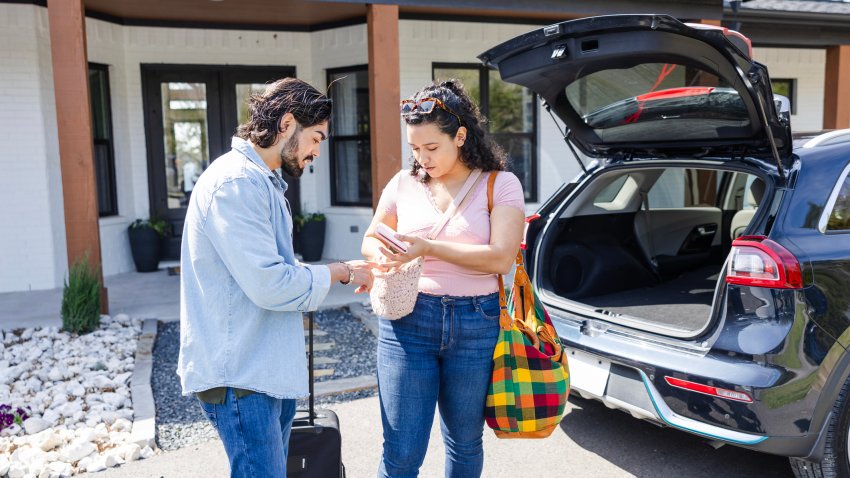Before loading their luggage into the rental car, the young adult couple searches for their passports.