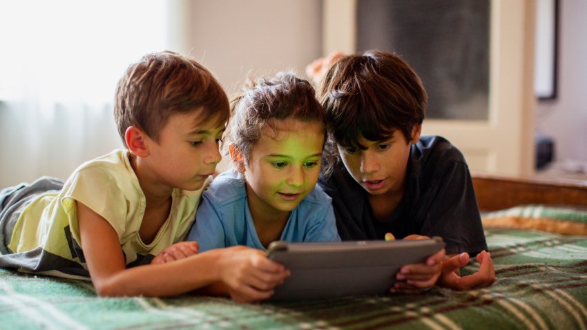 Cute boys using a digital tablet, lying on bed, in daylight