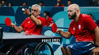 El francés Emeric Martin (izq.) saca una pelota junto al francés Maxime Thomas durante el partido de dobles de tenis de mesa masculino de octavos de final (clase 4-3) entre Eslovaquia y Francia en los Juegos Paralímpicos de París 2024 en el South Paris Arena en París, el 29 de agosto de 2024.