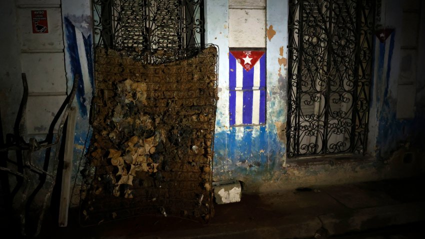 ACOMPAÑA CRÓNICA CUBA APAGONES AME8952. LA HABANA (CUBA), 19/10/2024.- Fotografía de un colchón dañado junto a una bandera de Cuba durante un apagón este viernes, en La Habana, (Cuba). Cuando de verdad se sufre el apagón es de noche. Cuando las casas quedan totalmente a oscuras, las cocinas eléctricas no sirven para preparar la cena, los ventiladores inertes no espantan el calor caribeño y sólo las luces de un carro o un celular rompen el negro más rotundo. EFE/ Ernesto Mastrascusa