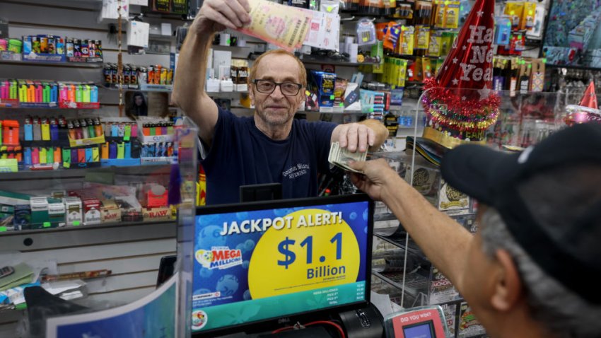 MIAMI, FLORIDA – DECEMBER 26: Robert Hadad sells Mega Millions lottery tickets to Carlos Rodriguez at his Downtown Miami Souvenirs store on December 26, 2024 in Miami, Florida. The Mega Millions jackpot has climbed to $1.15 billion ahead of Friday’s drawing, making it the fifth-largest prize in the game’s history and the largest prize ever offered in the month of December (Photo by Joe Raedle/Getty Images)