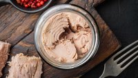 Canned tuna fillet meat in olive oil, on black background, flat lay