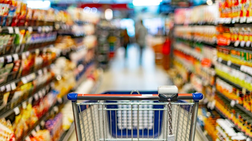 A shopping cart by a store shelf in a supermarket.