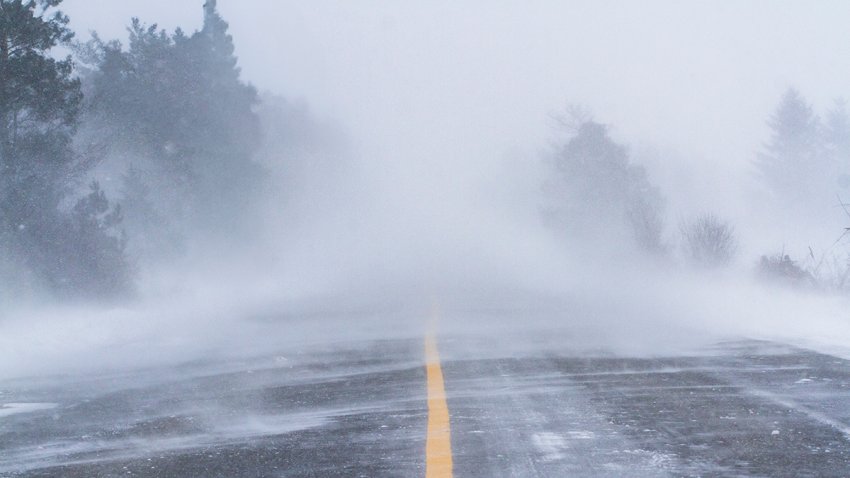 Fierce blizzard covers a strip of road with snow. Winter road conditions.