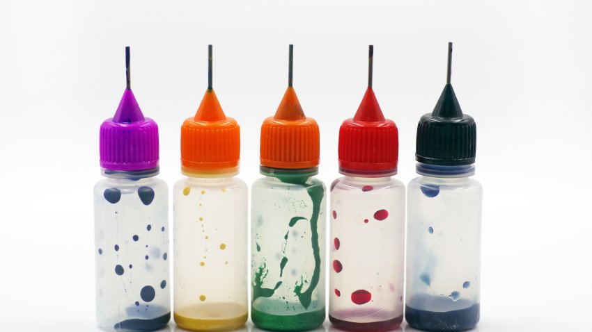 Five almost empty plastic bottles of food coloring against a white background
