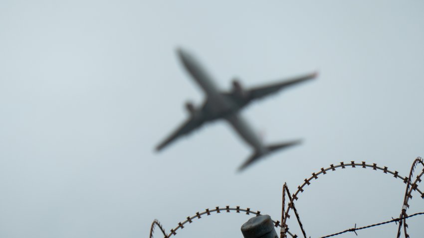 A Virgin Australia Boeing B737-8FE plane, registration VH-VON, takes off from Sydney Kingsford Smith Airport as flight VA481 to the Sunshine Coast.  In the foreground is part of the airport’s security fence. This image was taken from Vickers Avenue, Mascot on a rainy and overcast afternoon 30 November 2024.