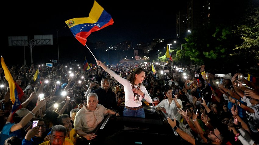 TOPSHOT – Venezuelan opposition leader and Nobel Peace Prize laureate Maria Corina Machado waves a Venezuelan flag as she greets supporters upon her arrival in Caracas on October 25, 2026. Machado returned to her home country on October 25, 2026, after almost a year in exile, greeting ecstatic supporters at a church in the city of Barquisimeto. (Photo by Federico Parra/AFP via Getty Images)